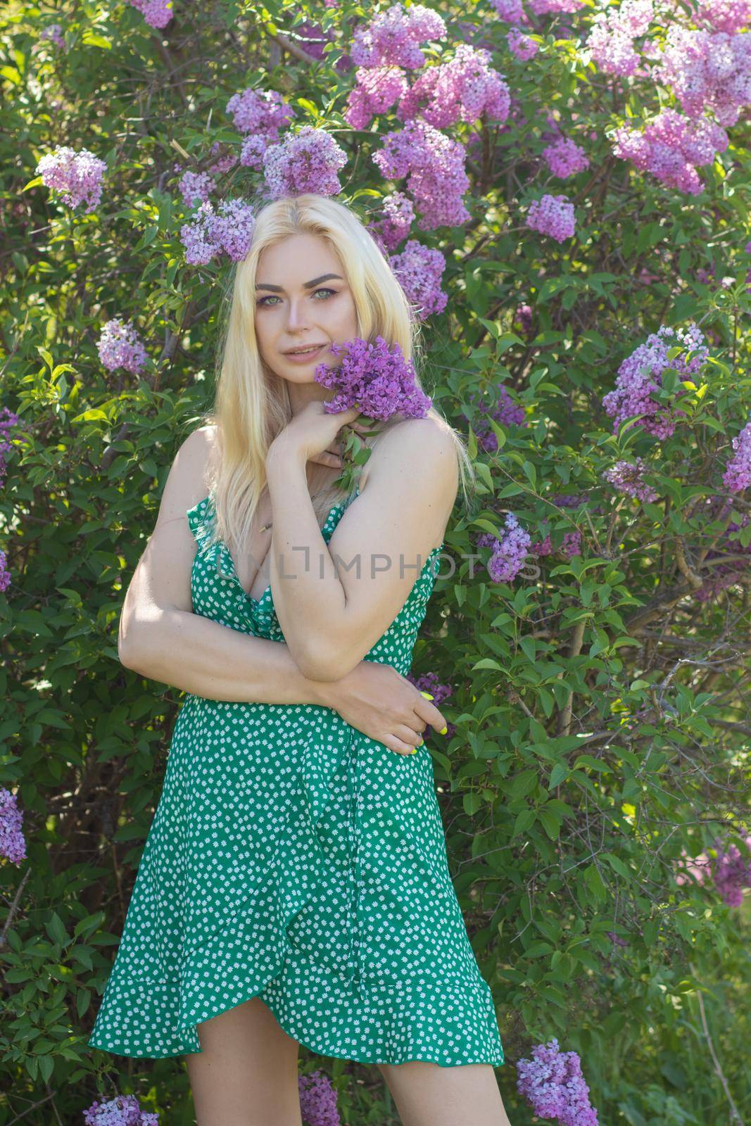 Fashionable girl model near a lilac bush. Spring flowers and beautiful blonde woman. Model appearance. Soft focus