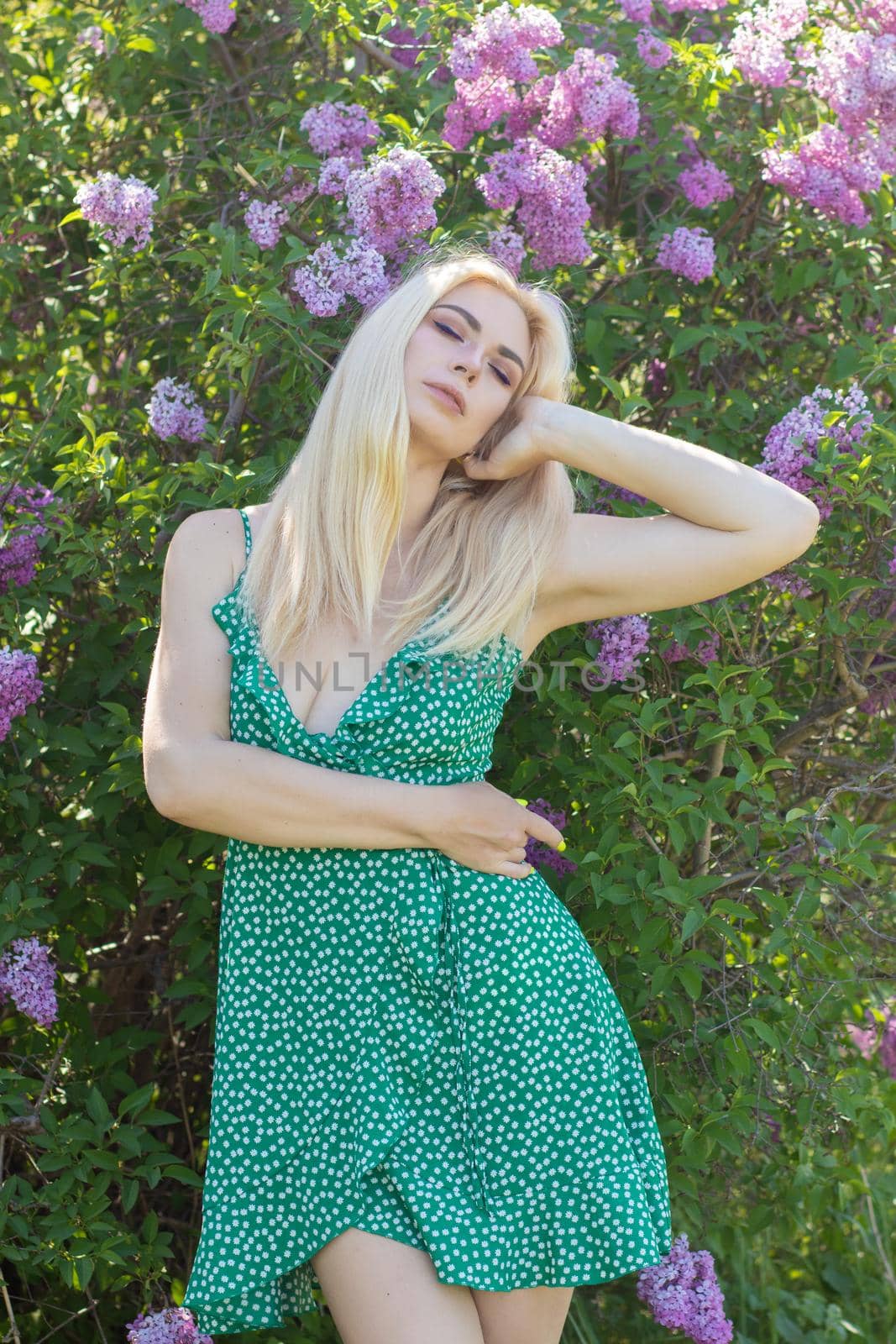 Fashionable girl model near a lilac bush. Spring flowers and beautiful blonde woman. Model appearance. Soft focus