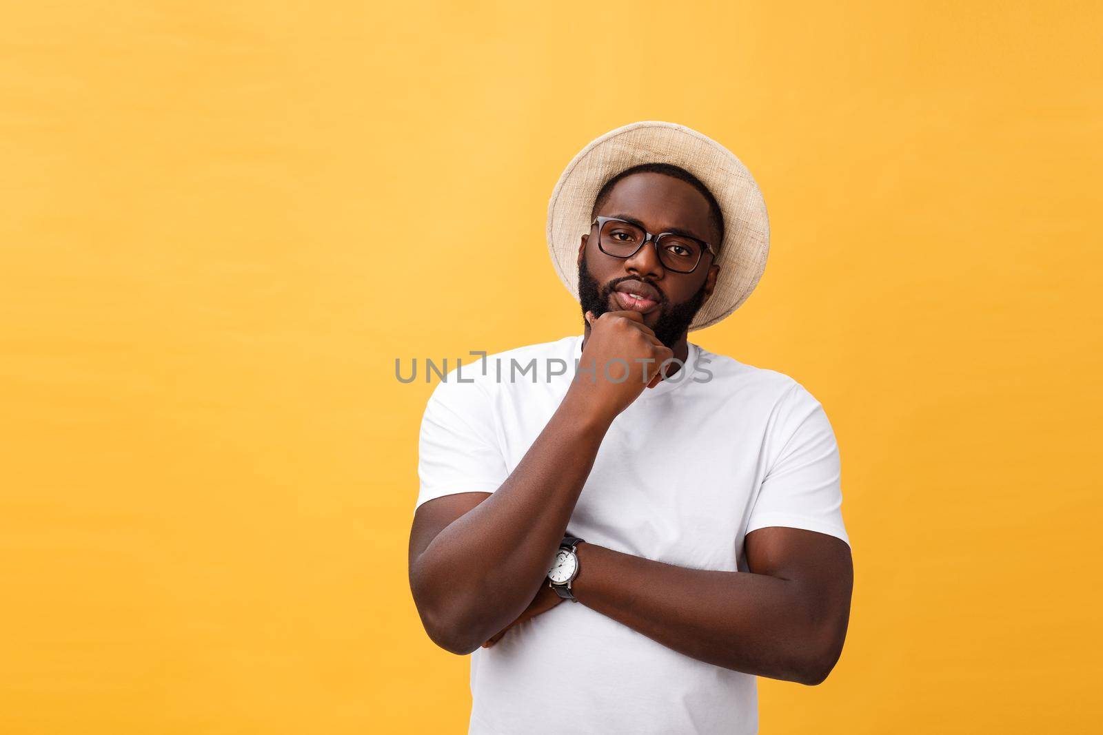 Portrait of a pensive afro american man in glasses looking up at copyspace isolated on a yellow background.