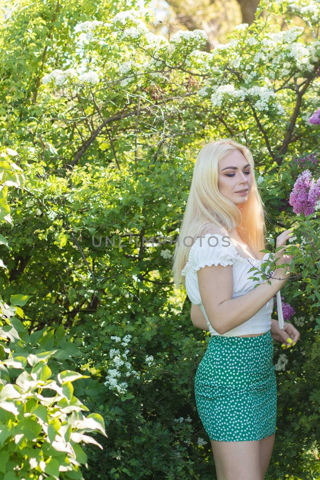 Fashionable girl model near a lilac bush. Spring flowers and beautiful blonde woman. Model appearance. Soft focus