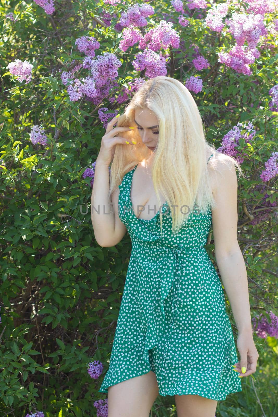 Fashionable girl model near a lilac bush. Spring flowers and beautiful blonde woman. Model appearance. Soft focus