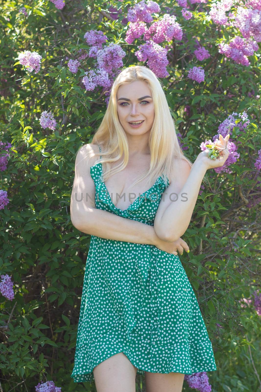 Fashionable girl model near a lilac bush. Spring flowers and beautiful blonde woman. Model appearance. Soft focus