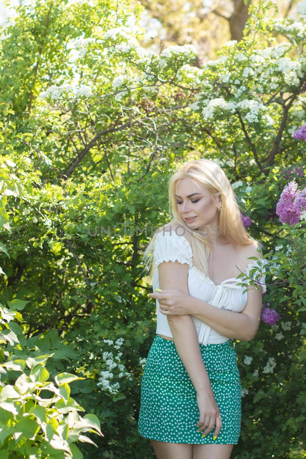 Fashionable girl model near a lilac bush. Spring flowers and beautiful blonde woman. Model appearance. Soft focus