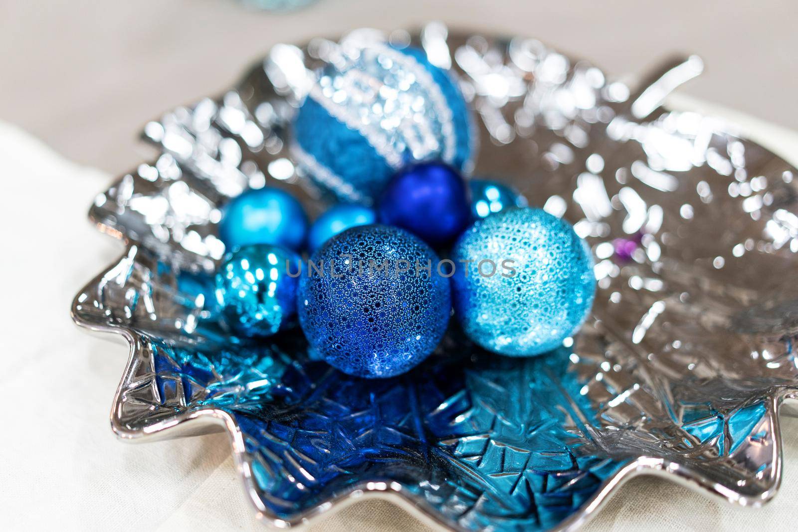 Shining Blue Christmas Decorations on Silver Plate. New Year Inspiration Still Life. Beautiful still life with round blue Christmas decorations. Close up shot.