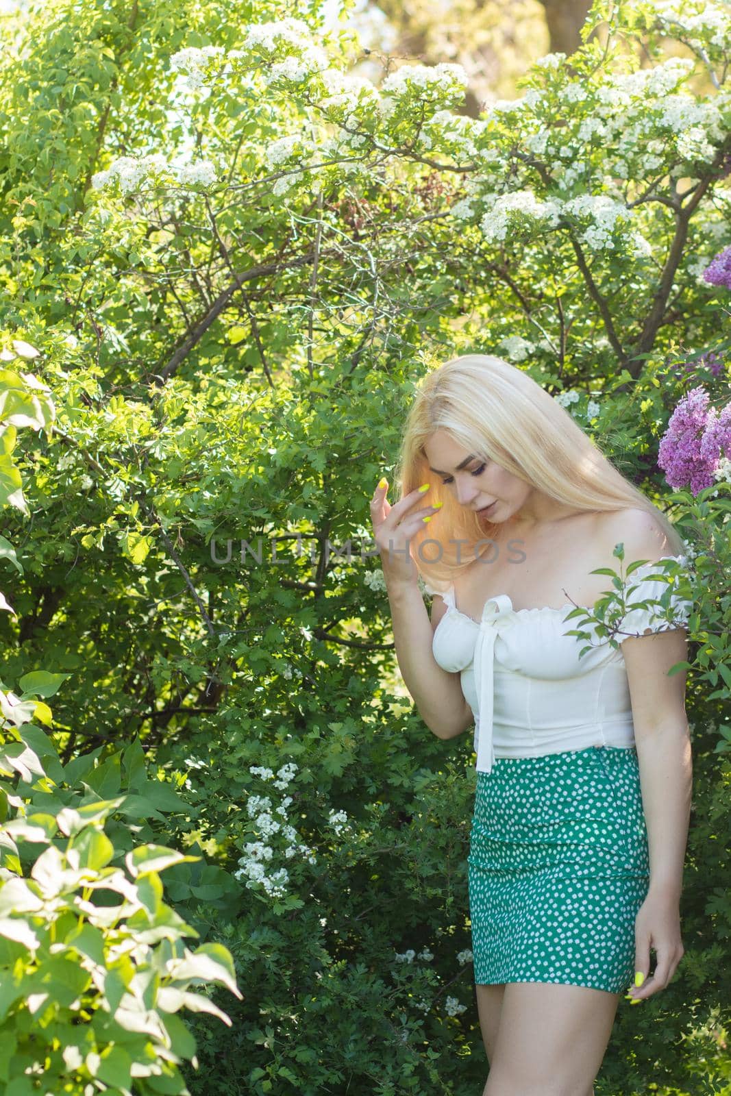 Fashionable girl model near a lilac bush. Spring flowers and beautiful blonde woman. Model appearance. Soft focus