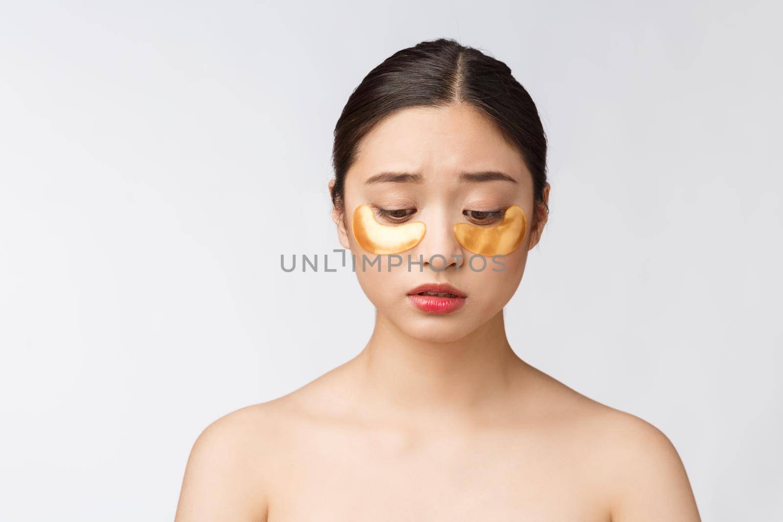 Asian beauty teenager woman care her skin with gold eye masks patches under eyes with worry. by Benzoix