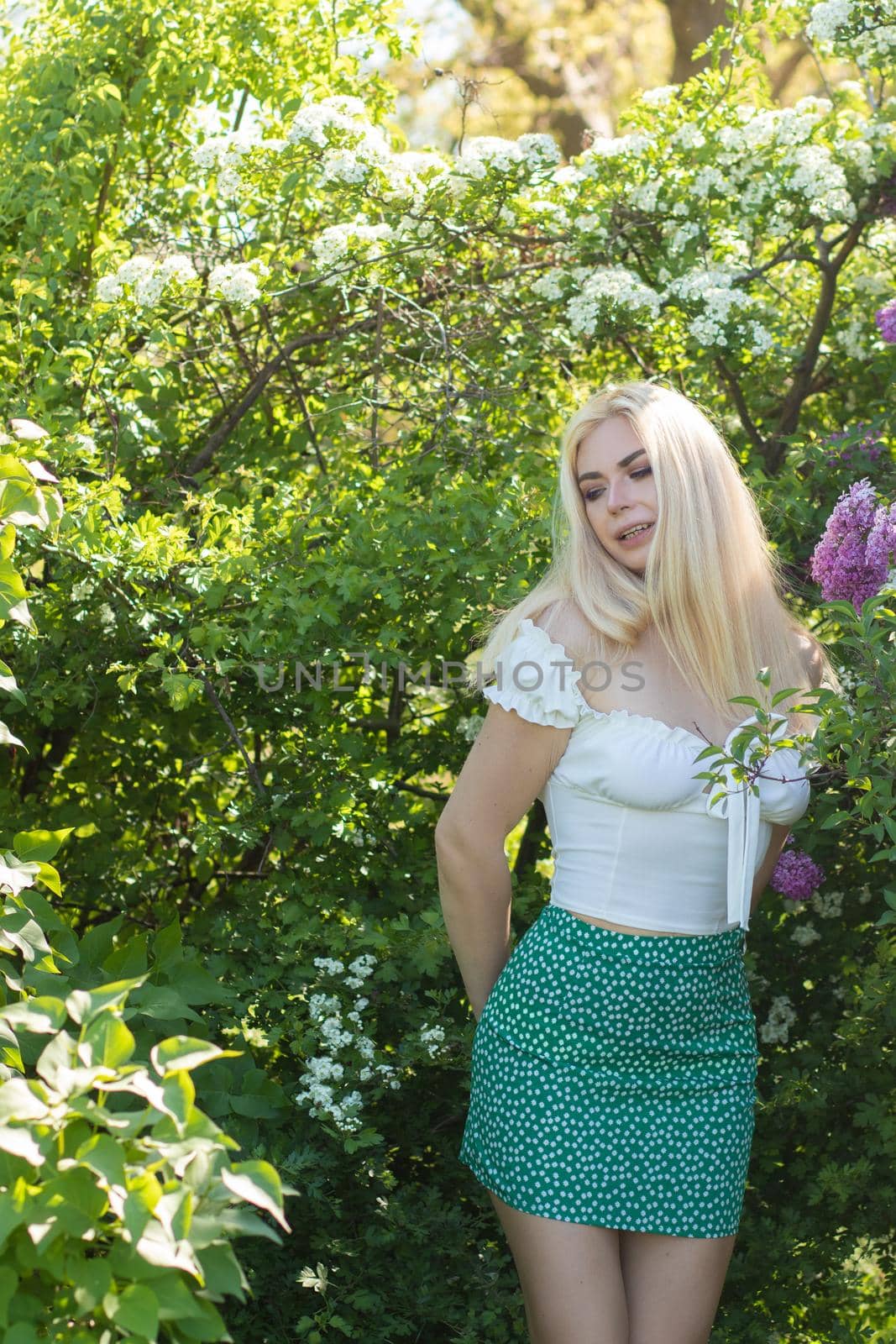 Fashionable girl model near a lilac bush. Spring flowers and beautiful blonde woman. Model appearance. Soft focus