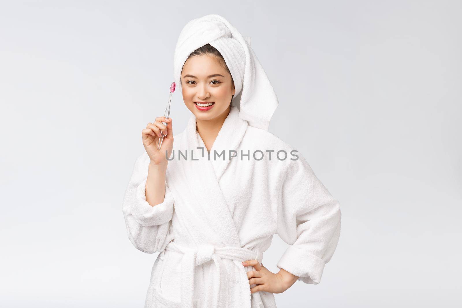 Asian happy woman with toothbrush in bathrobe morning mood.