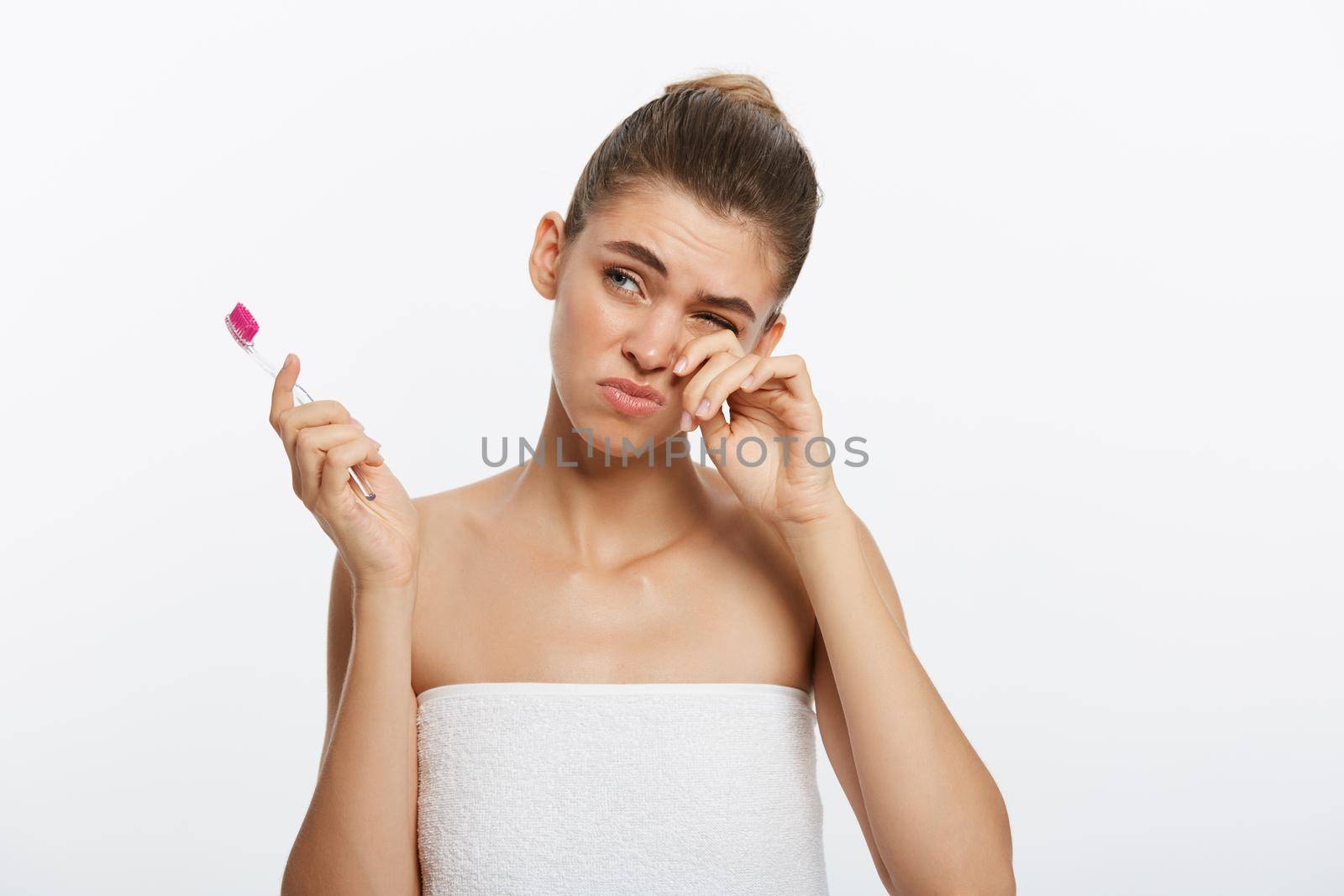 Beauty portrait of a happy beautiful half naked woman brushing her teeth with a toothbrush and looking at camera isolated over white background.