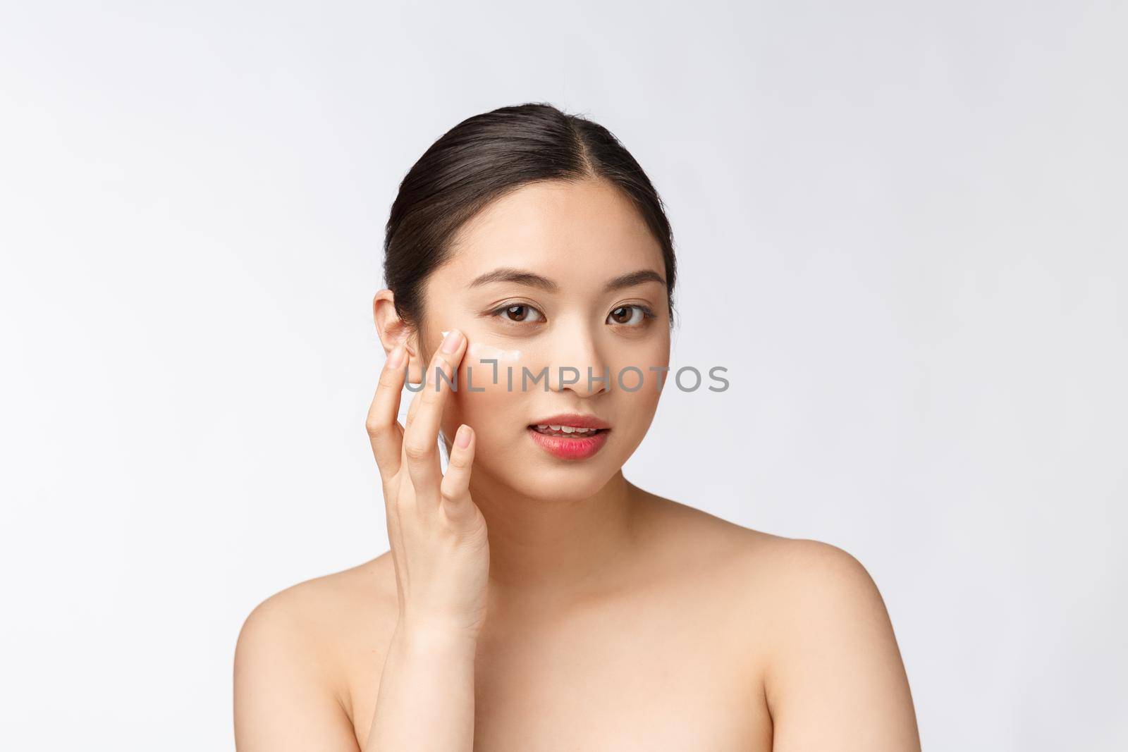 Skin care beauty woman. Beauty woman smiling applying cream. Beauty portrait of beautiful Asian Caucasian female model isolated on white