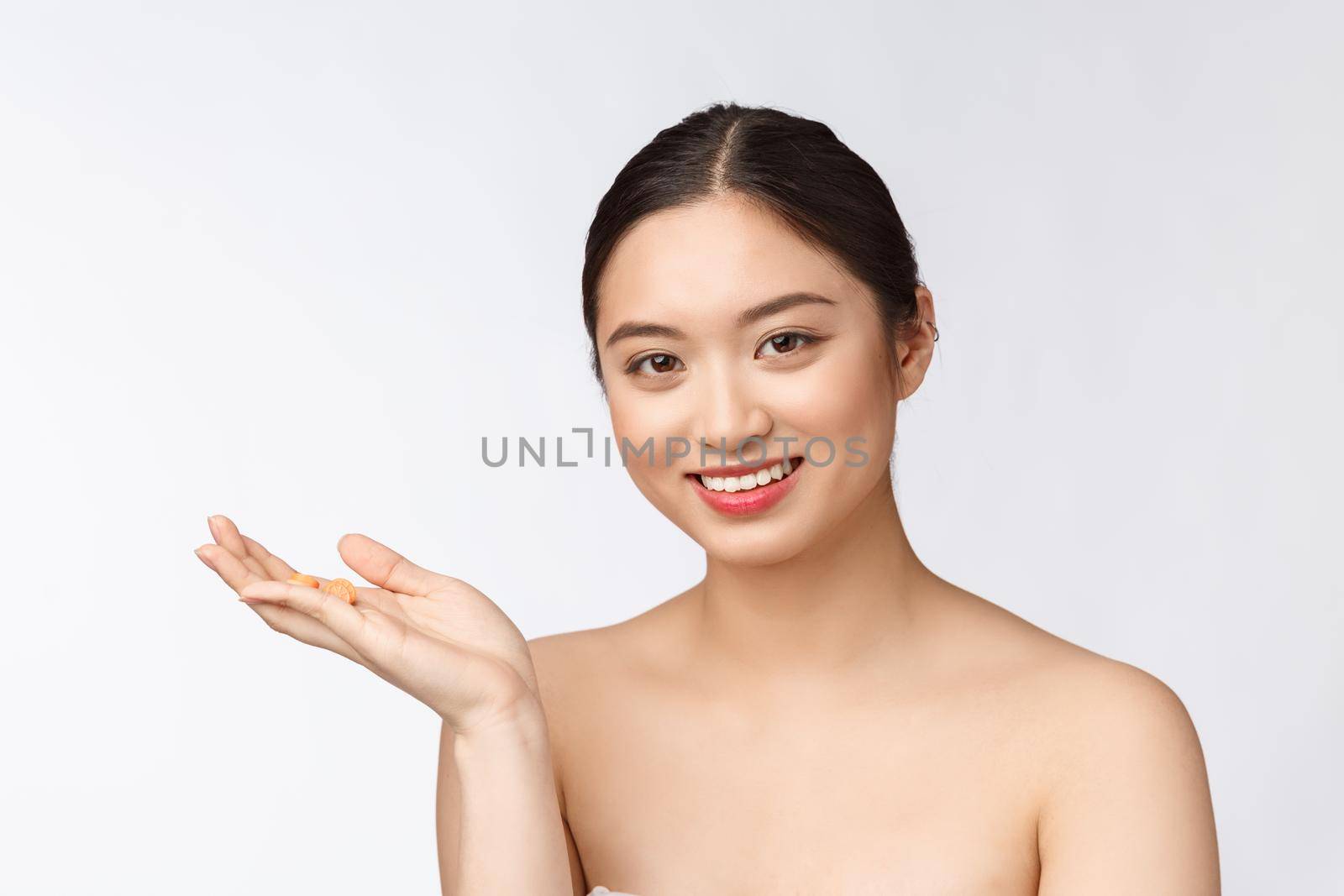 Young attractive asian woman who takes a capsule or pill. Isolated over white background