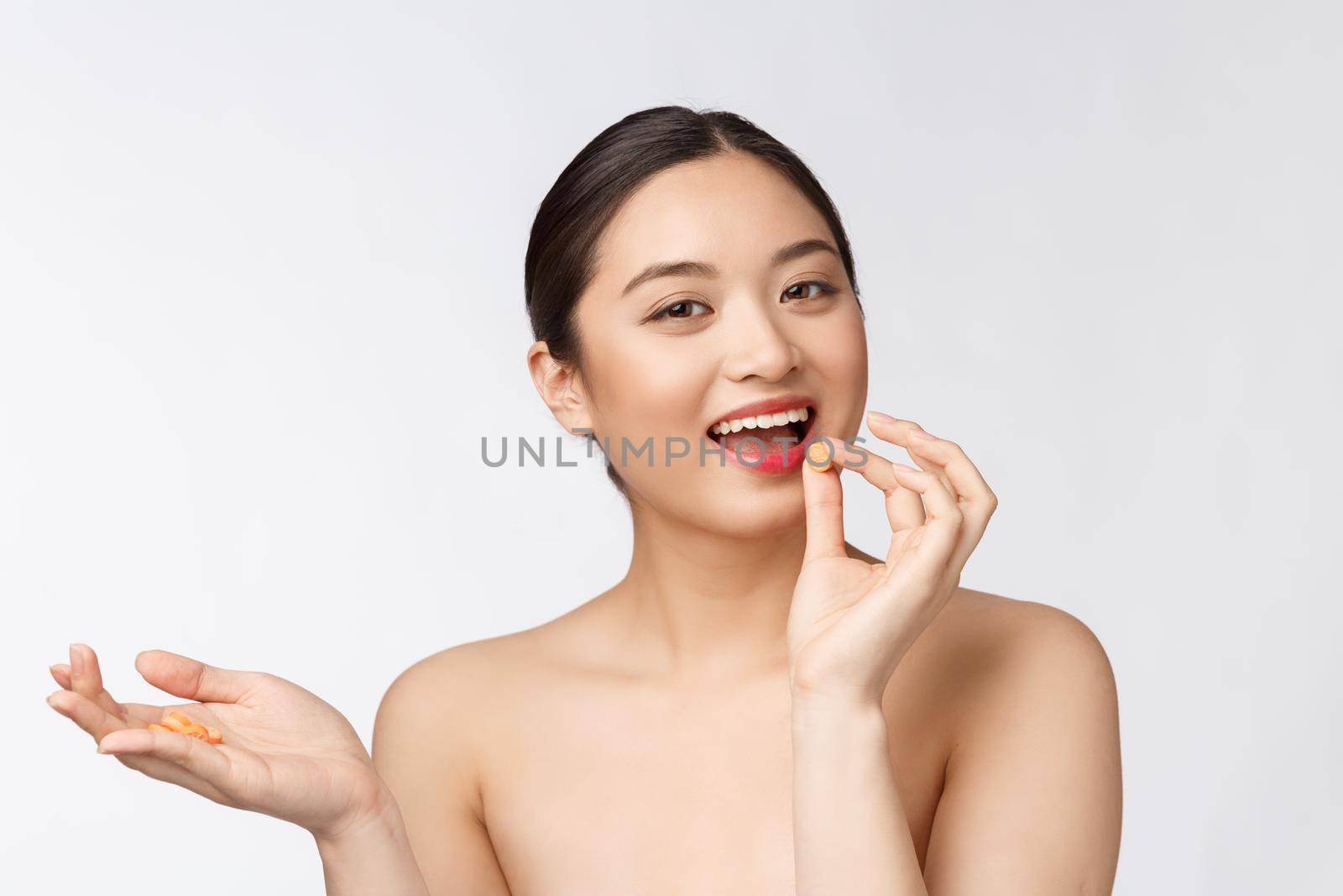 Young attractive asian woman who takes a capsule or pill. Isolated over white background