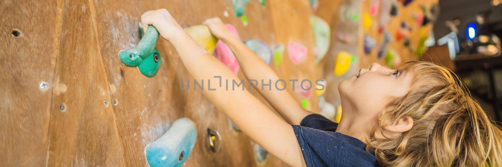 little boy climbing a rock wall in special boots. indoor BANNER, LONG FORMAT by galitskaya