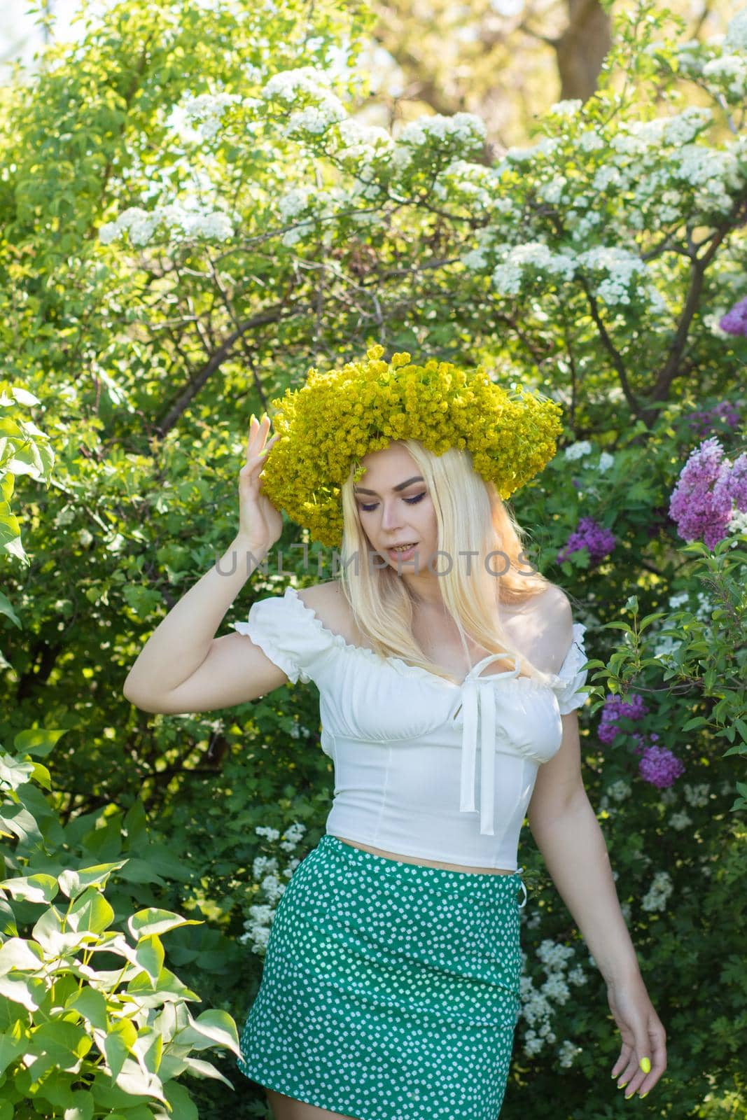 Beautiful woman in lilac Garden. Girl with yellow flower wreath in springtime. Gardening. Soft focus