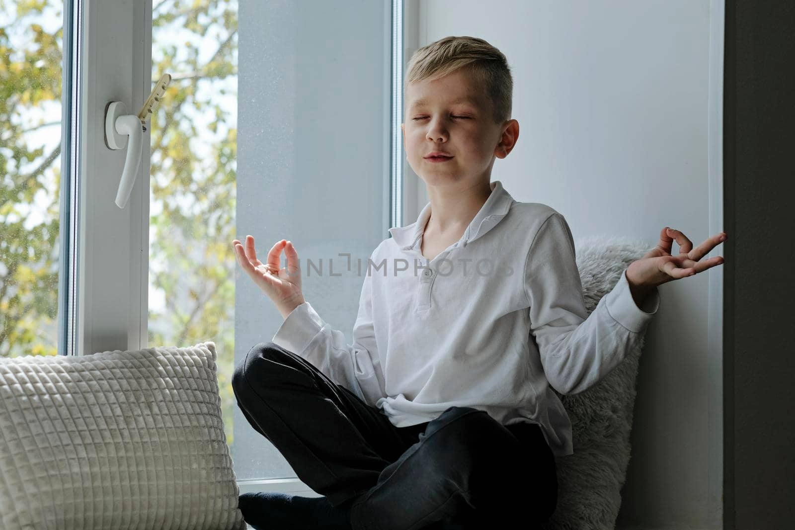 Cute school boy reading sitting on a windowsill and meditatig by natus111