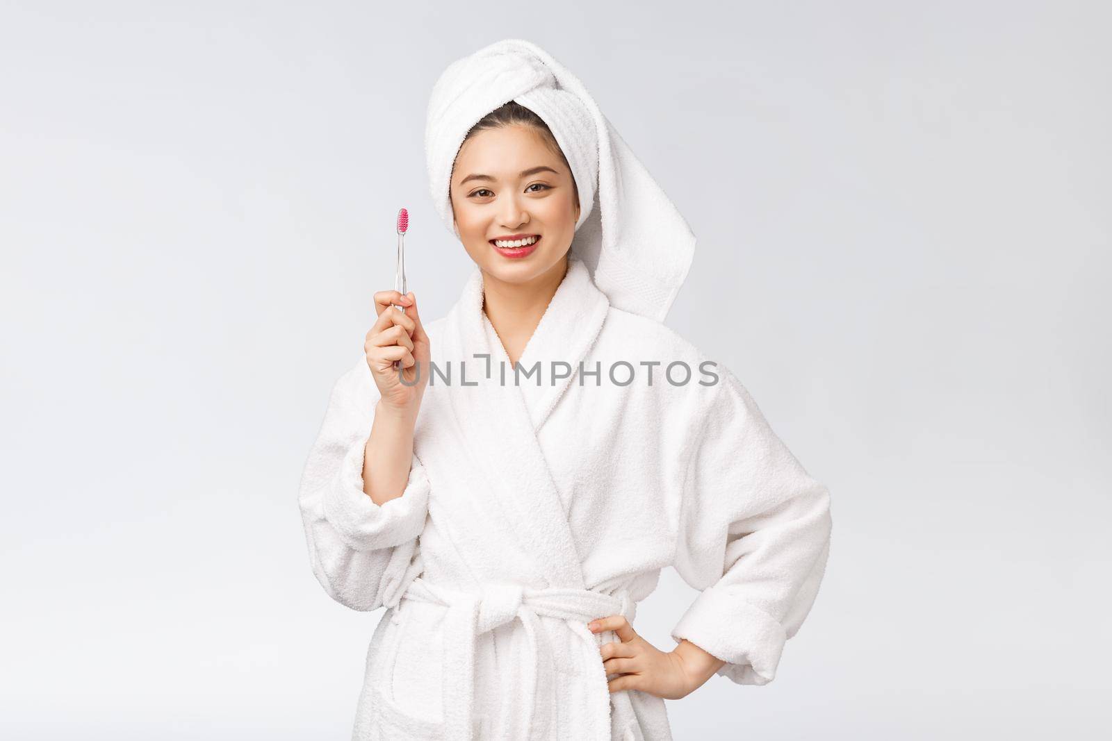 Asian happy woman with toothbrush in bathrobe morning mood.