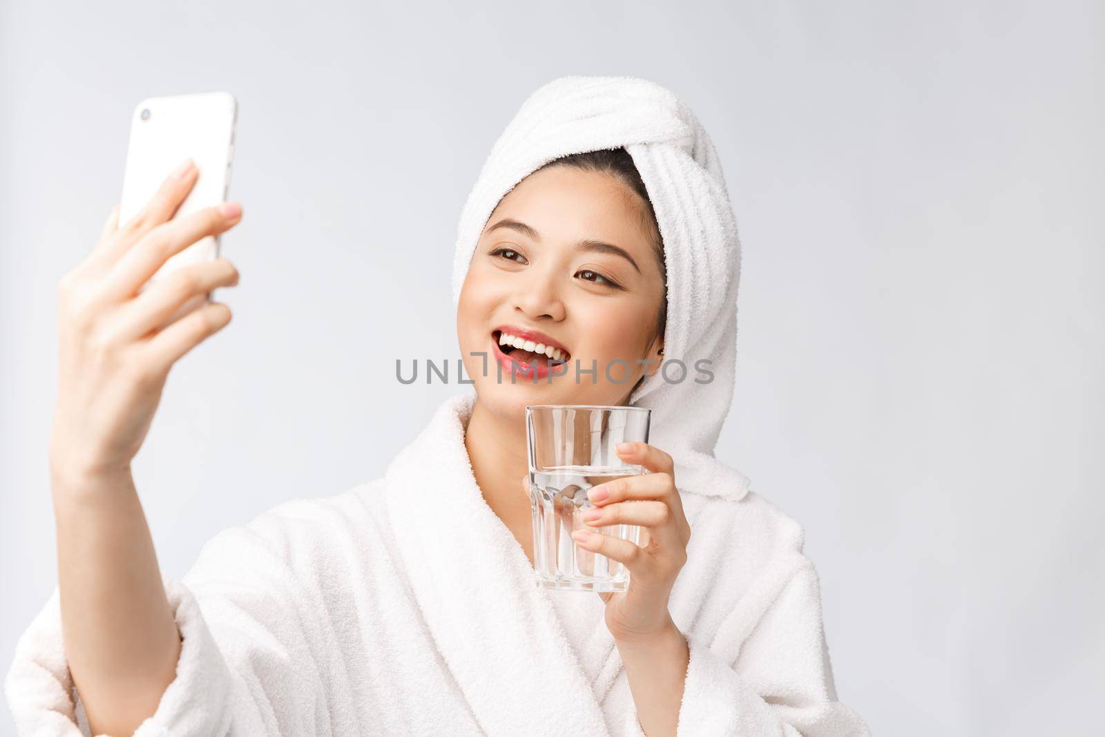 Healthy young beautiful woman drinking water, beauty face natural makeup with holding mobile phone, isolated over white background