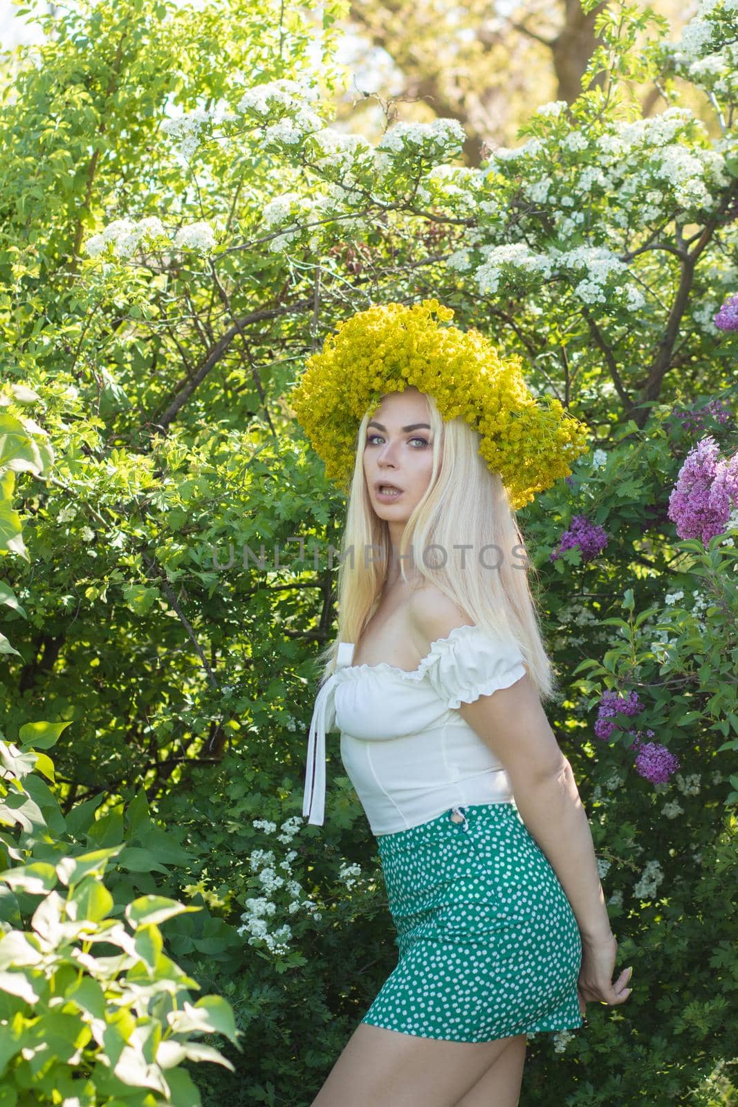 Beautiful woman in lilac Garden. Girl with yellow flower wreath in springtime. Gardening. Soft focus