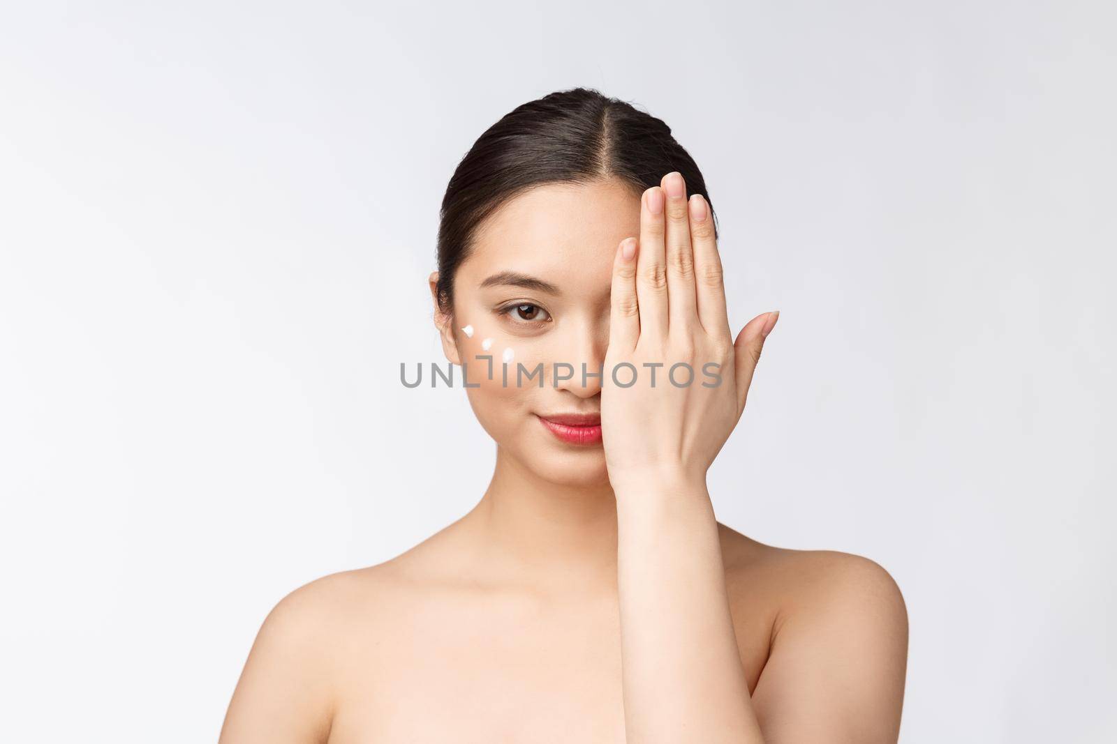 Skin care beauty woman. Beauty woman smiling applying cream. Beauty portrait of beautiful Asian Caucasian female model isolated on white