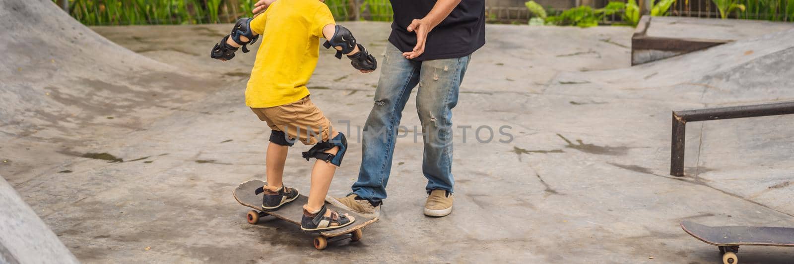 Athletic boy learns to skateboard with a trainer in a skate park. Children education, sports BANNER, LONG FORMAT by galitskaya