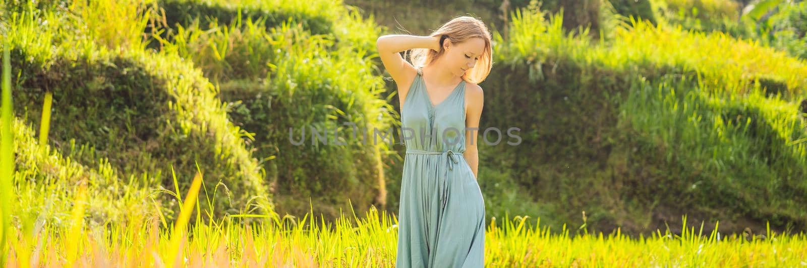 BANNER, LONG FORMAT Beautiful young woman walk at typical Asian hillside with rice farming, mountain shape green cascade rice field terraces paddies. Ubud, Bali, Indonesia. Bali travel concept.