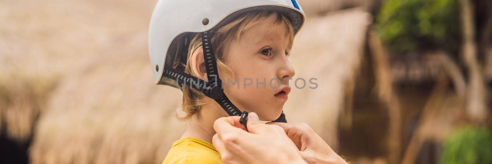 Trainer helps the boy to wear helmet before training skate board. BANNER, LONG FORMAT
