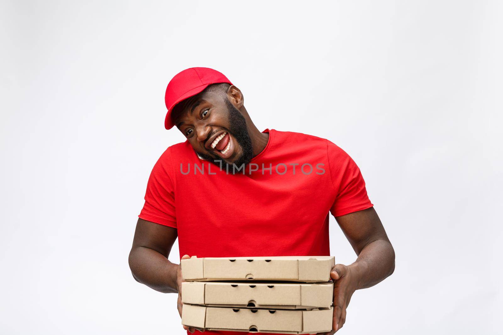 Delivery Concept: Handsome african pizza delivery man talking to mobile with shocking facial expression. Isolated over grey background