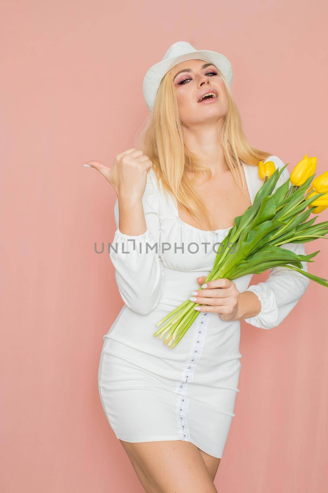 Woman in white dress and hat holding yellow tulips by Bonda