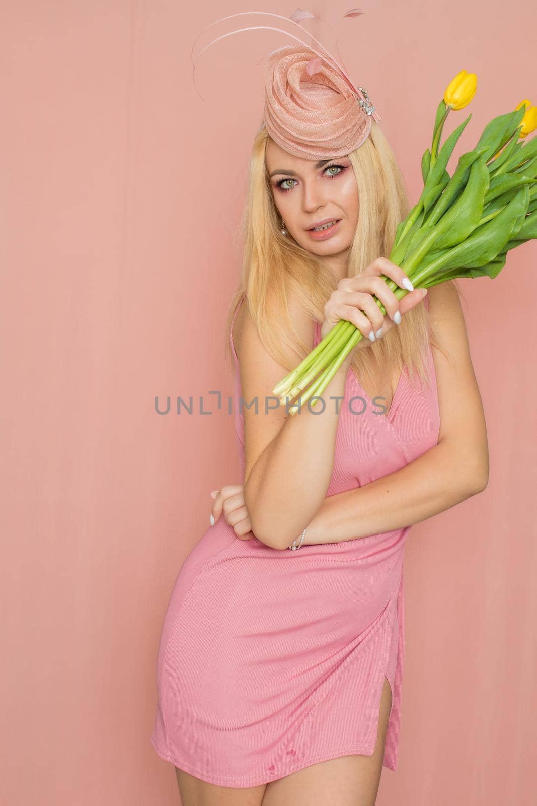 Blonde woman in pink hat holsing yellow tulips by Bonda