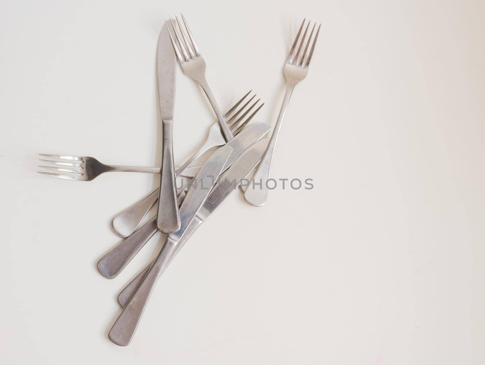 Food background - high angle view of four forks and knives scattered on white table with copy space to right by natalie_board