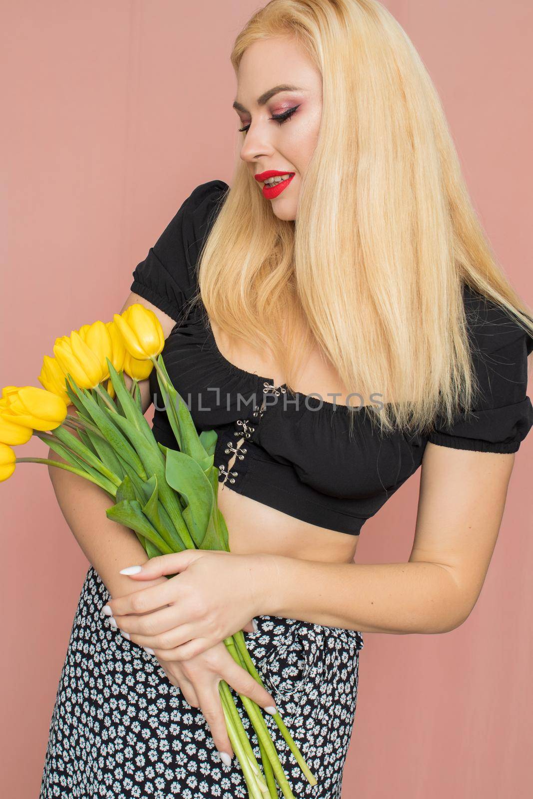 Woman in black top and skirt holding yellow tulips by Bonda