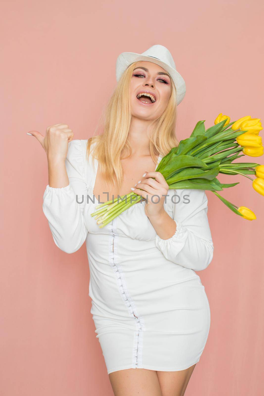 Woman in white dress and hat holding yellow tulips by Bonda