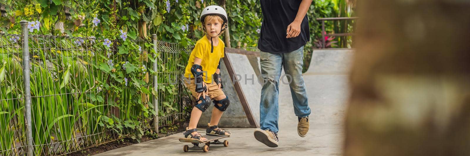 Athletic boy learns to skateboard with a trainer in a skate park. Children education, sports BANNER, LONG FORMAT by galitskaya