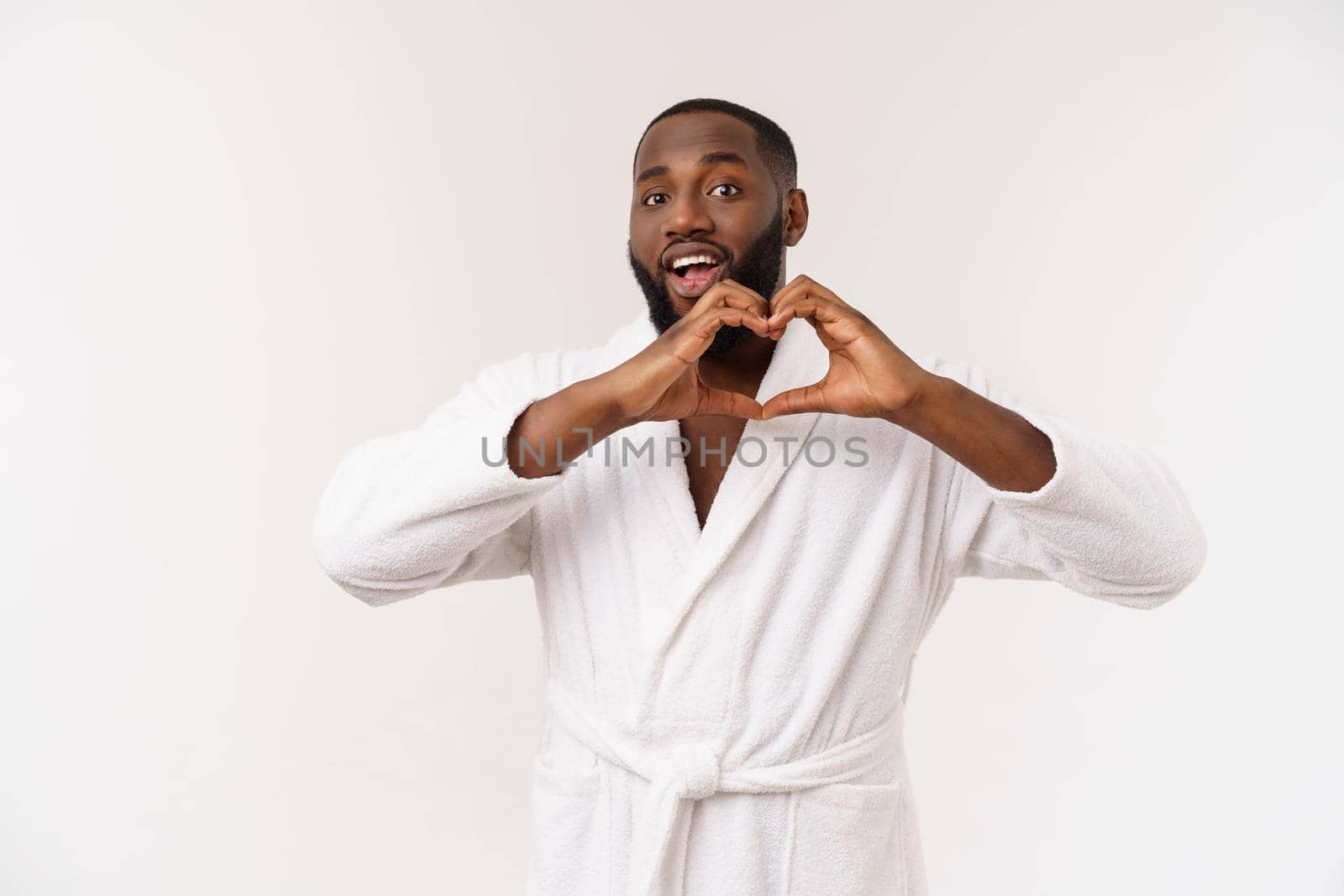 Portrait of creative, romantic, positive, cheerful, confident guy making love symbol, heart figure with fingers, looking at camera, isolated on grey background
