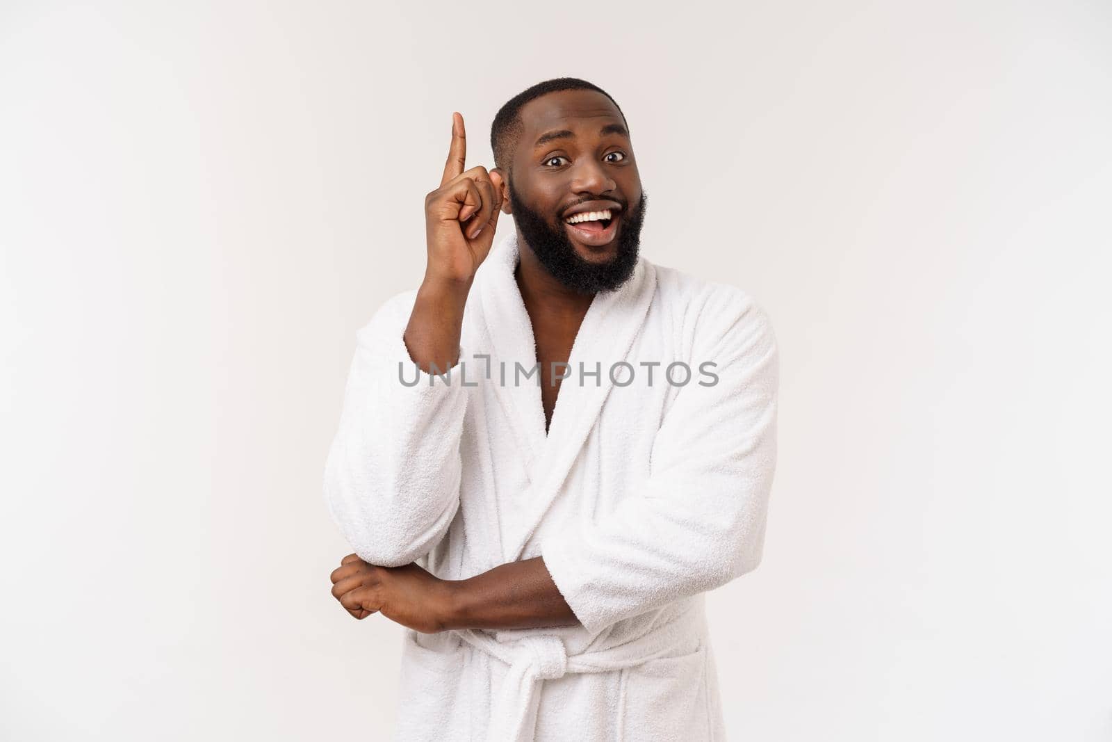 Black guy wearing a bathrobe pointing finger with surprise and happy emotion. Isolated over whtie background