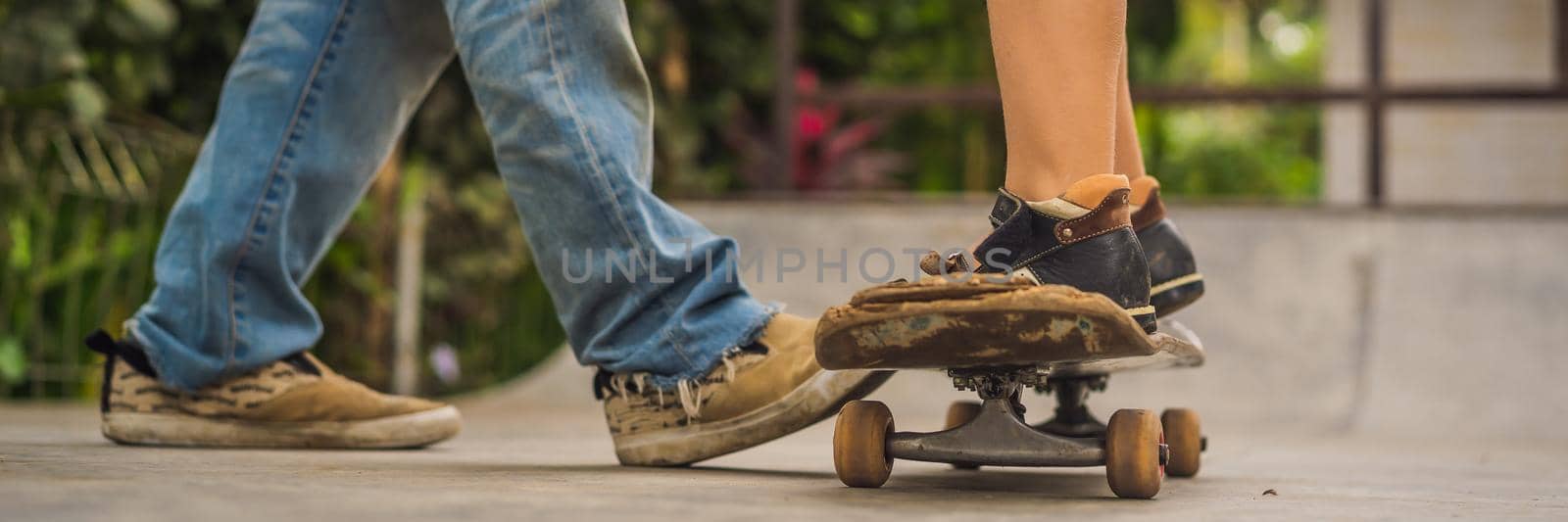 Athletic boy learns to skateboard with a trainer in a skate park. Children education, sports. BANNER, LONG FORMAT