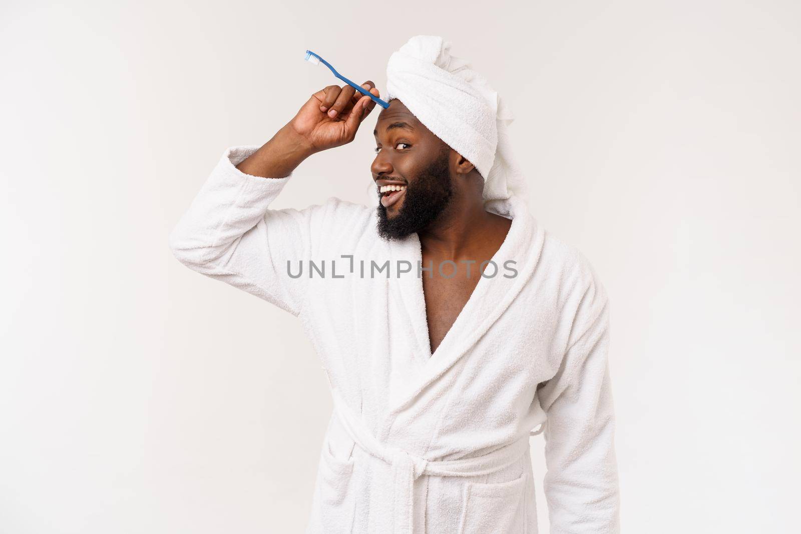 portrait of a happy young dark-anm brushing his teeth with black toothpaste on a white background