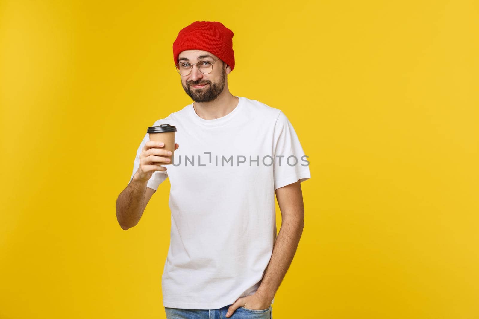 Man on isolated vibrant yellow color taking a coffee in takeaway paper cup and smiling because he will start the day well