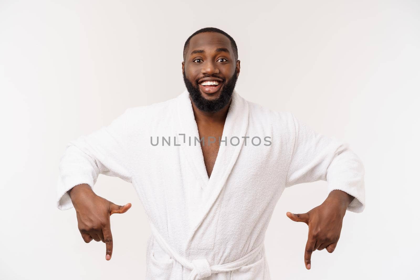 Black guy wearing a bathrobe pointing finger with surprise and happy emotion. Isolated over whtie background