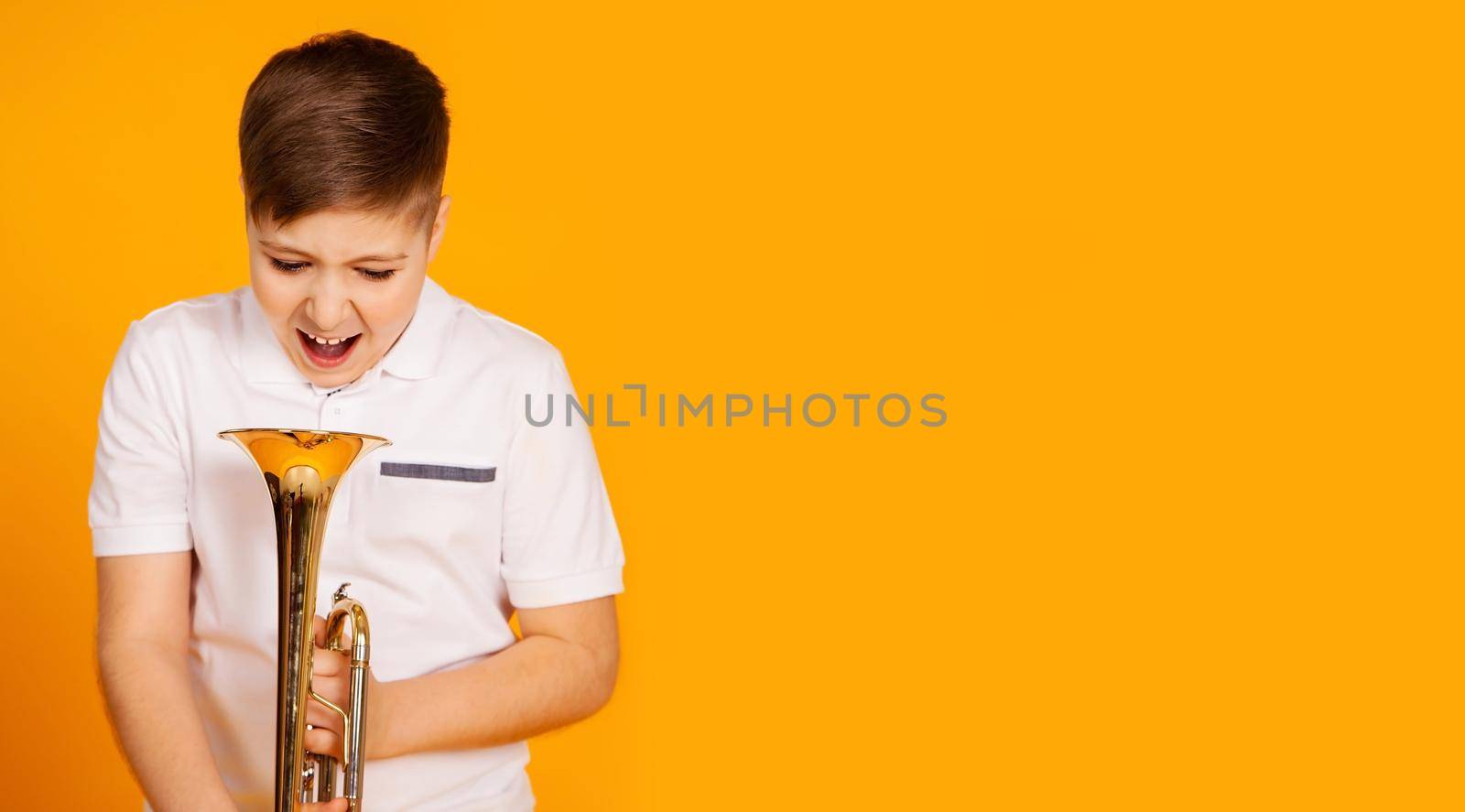 The boy screams into the pipe. Annoyed displeased boy shows his anger