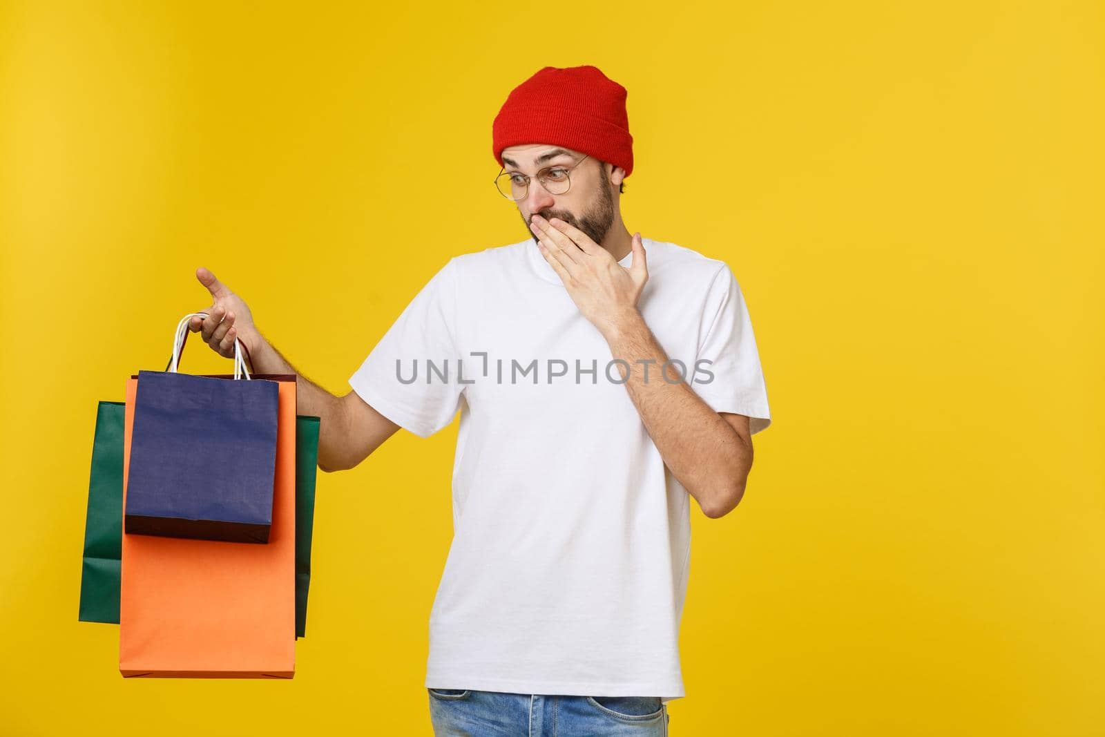 Bearded man with shopping bags with happy feeling isolated on yellow bacground.