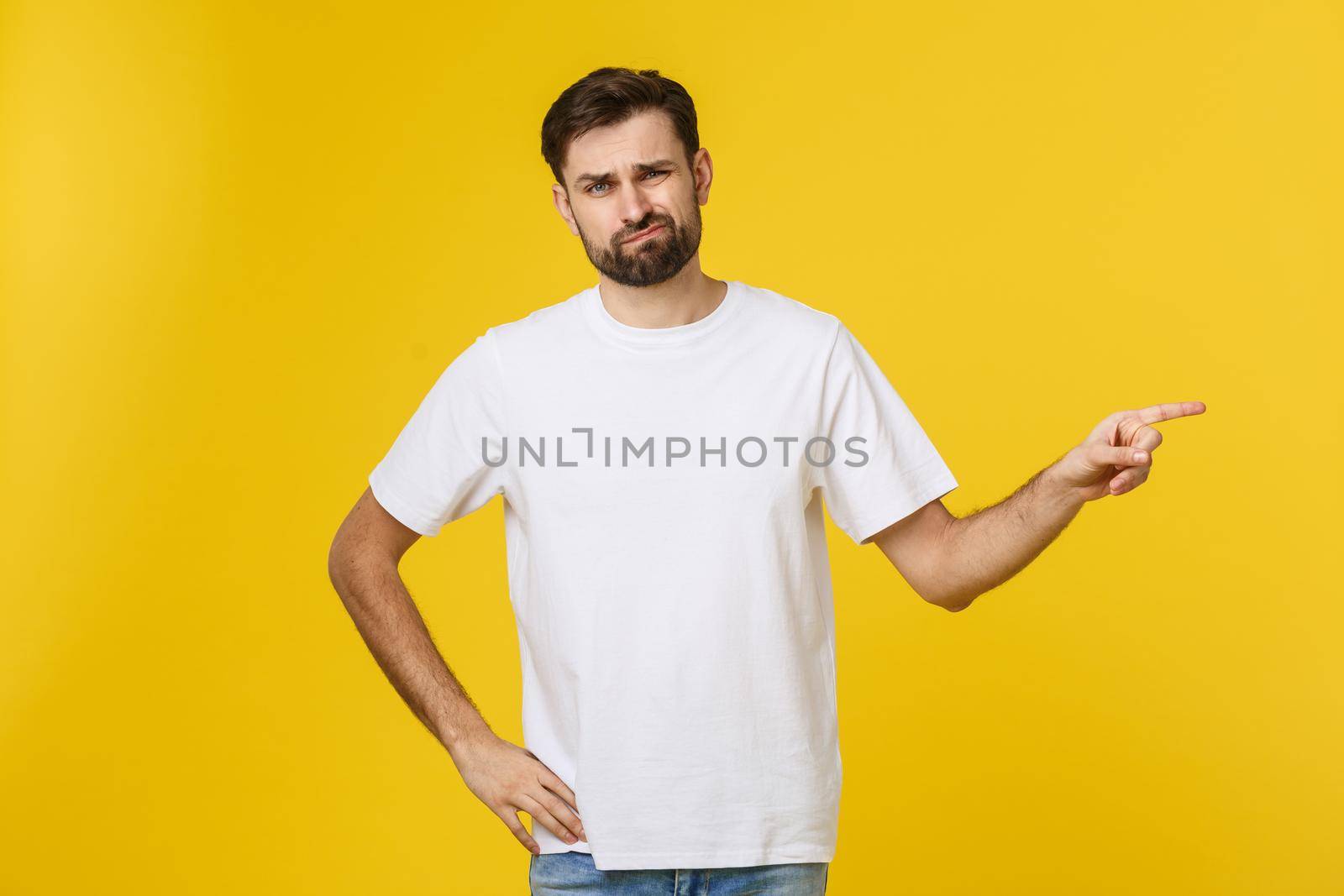 Handsome man over isolated yellow wall frustrated and pointing to the front