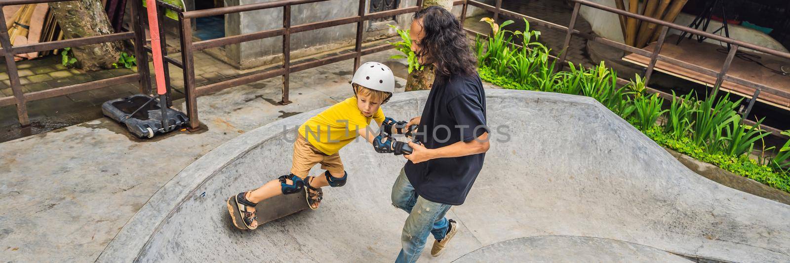 Athletic boy learns to skateboard with a trainer in a skate park. Children education, sports. BANNER, LONG FORMAT