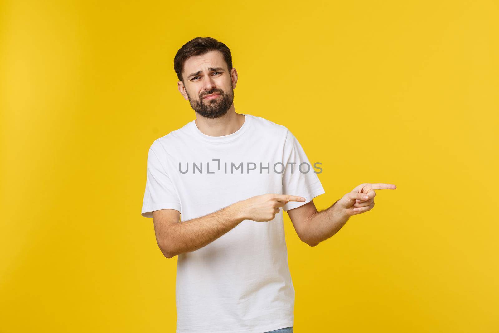 Handsome man over isolated yellow wall frustrated and pointing to the front. by Benzoix