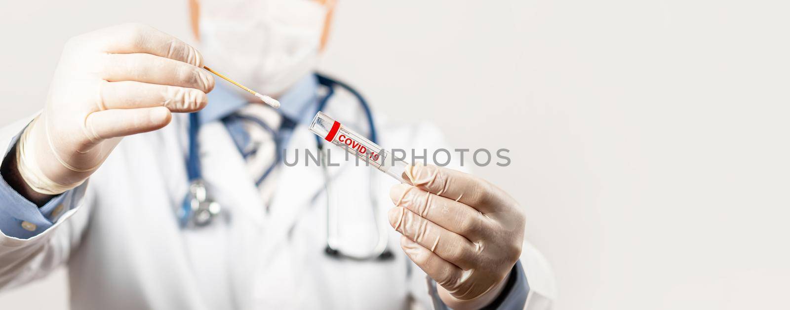 Test for coronavirus Covid-19. Male doctor or nurse doing nasal swab laboratory analysis in a hospital laboratory. A medical technologist holds a COVID-19 smear kit by wearing protective gloves.