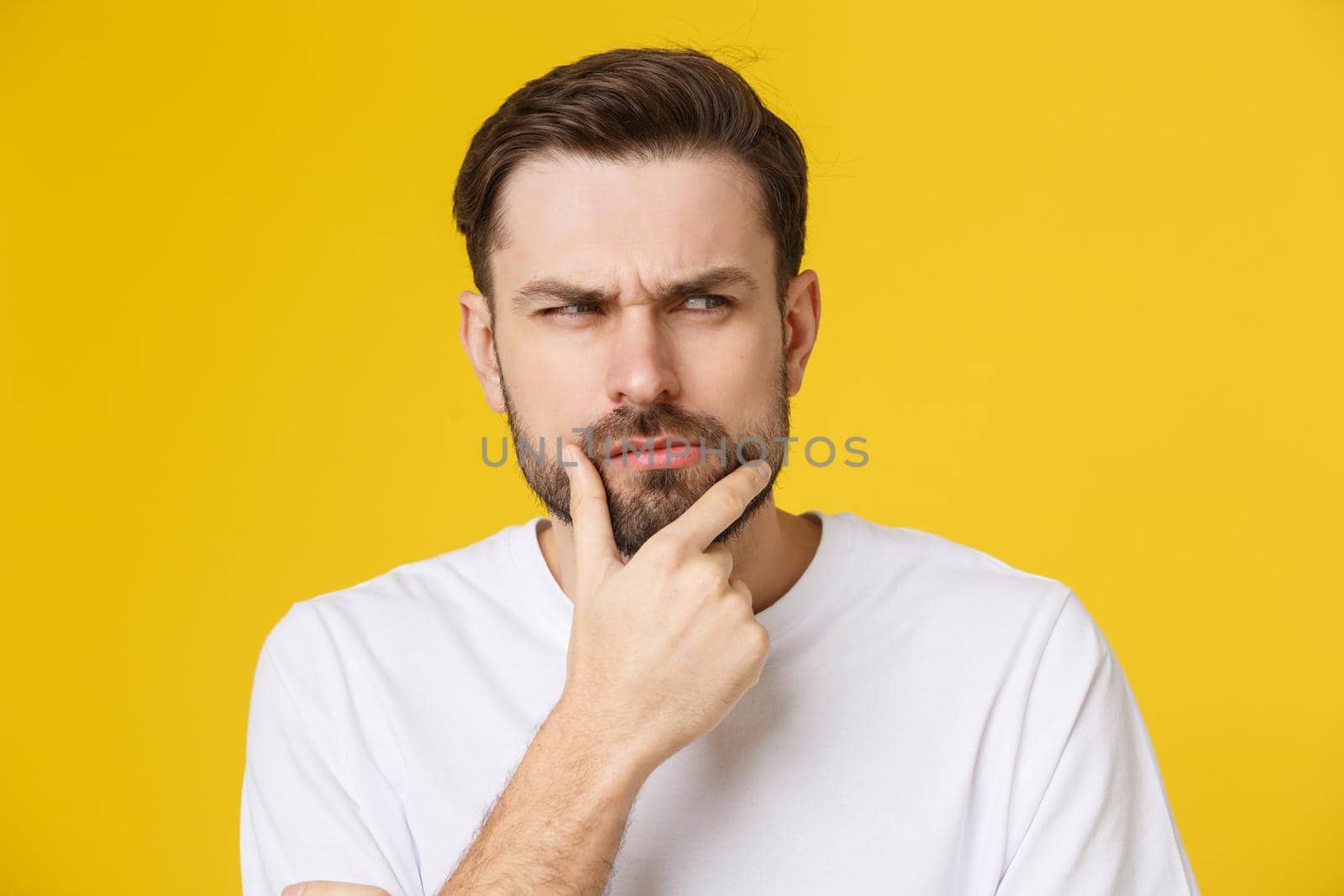 Thinking man isolated on yellow background. Closeup portrait of a casual young pensive man looking up at copyspace. Caucasian male model