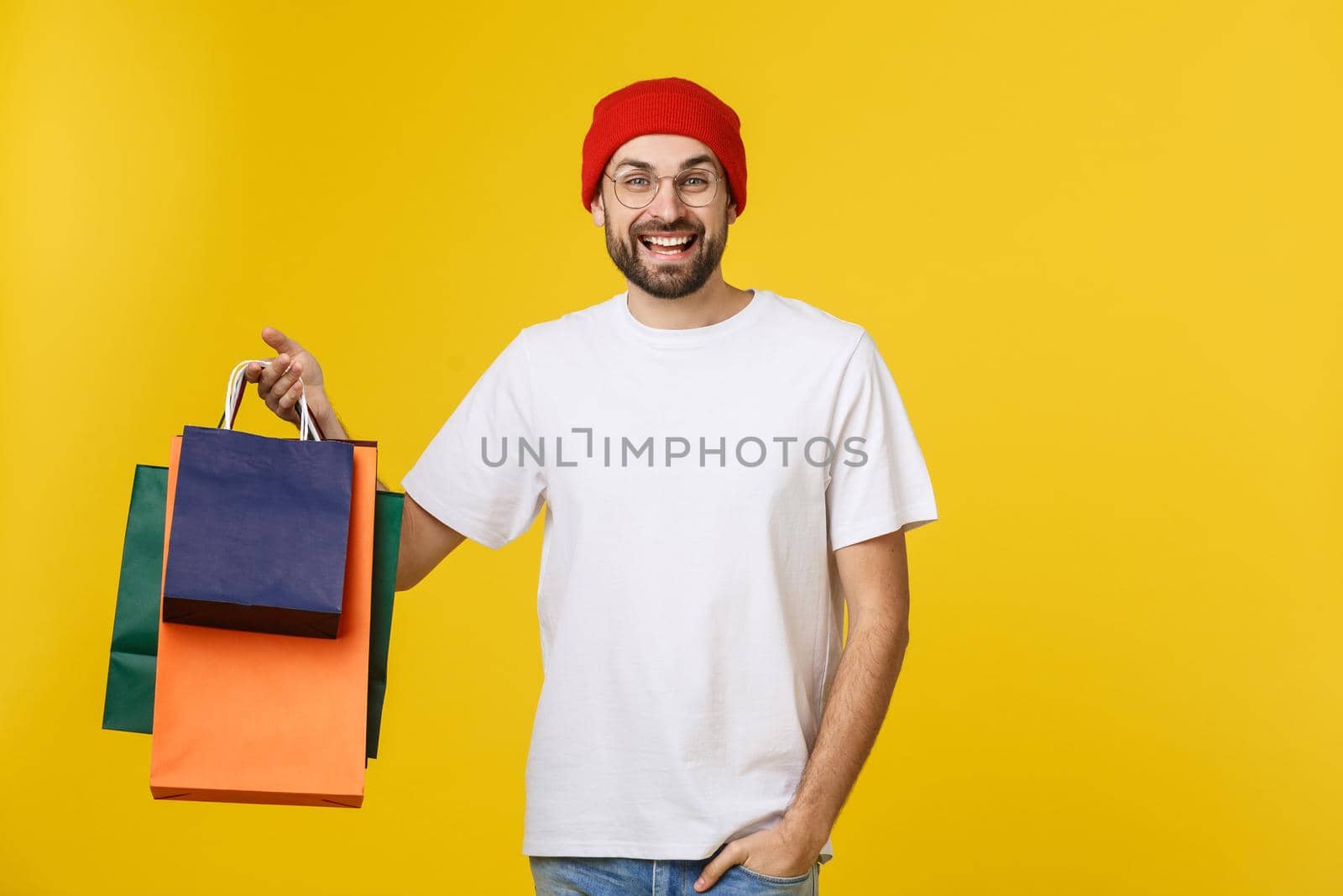 Bearded man with shopping bags with happy feeling isolated on yellow bacground.