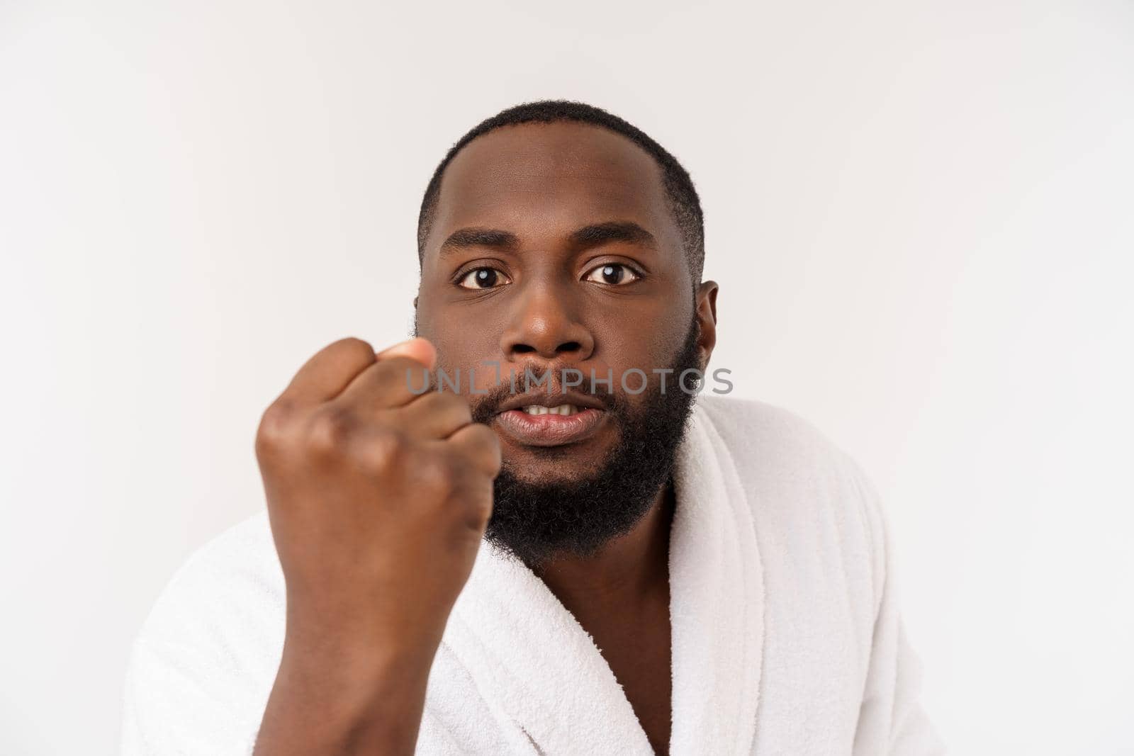 Black guy wearing a bathrobe pointing finger with surprise and happy emotion. Isolated over whtie background