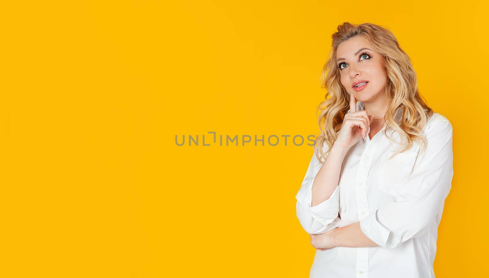 Curious modern stylish caucasian blond woman sideways look thinking make a choice thinking thinking delighted smile widely touching face thoughtful have an interesting idea desire
