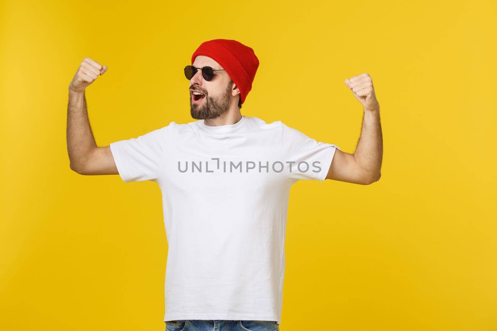 Successful young man celebrating against a yellow background